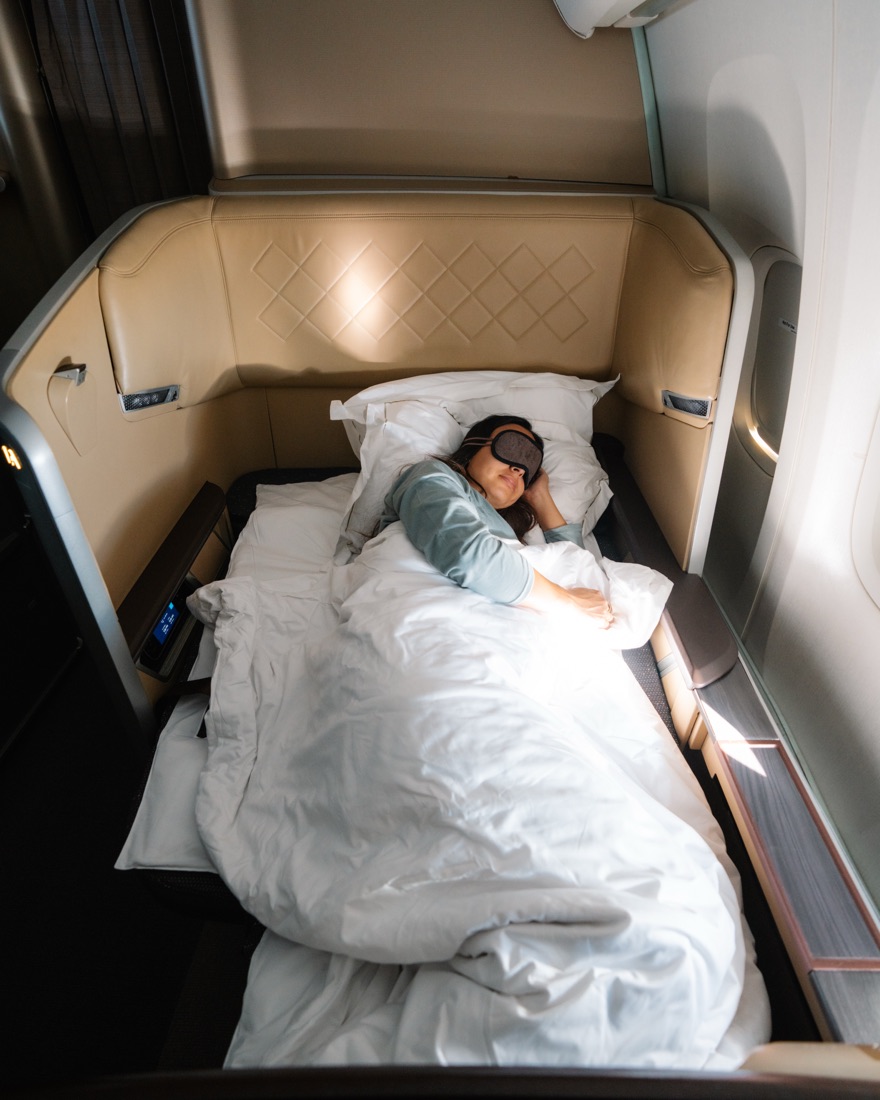 Catarina asleep in a made-up bed in Singapore Airlines First Class